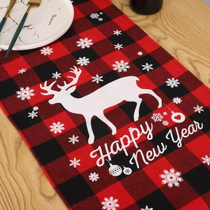 Détail d'un chemin de table de Noël à carreaux rouges et noirs avec motif renne et neige