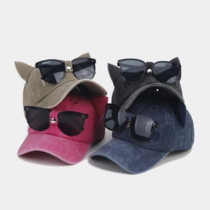 Detail of four baseball caps with cat ears and integrated pilot sunglasses in various colors