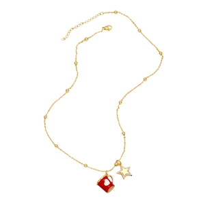 Detail of gold necklace with red mug charm, star pendant, and small golden beads