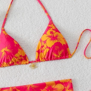 Detail of pink floral bikini top with tropical hibiscus print and gold flower charm