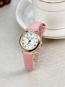 Detail view of pink leather strap watch with gold case and Roman numeral dial