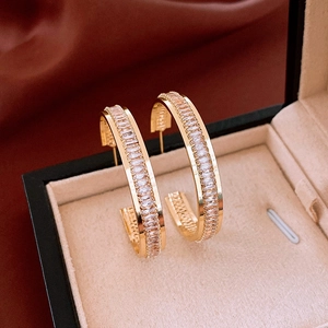 Macro view of gold hoop earrings with baguette-cut zircons in a jewelry box