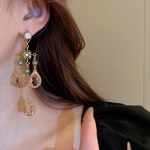 Close-up of vintage palace style gold drop earrings with champagne crystals on model