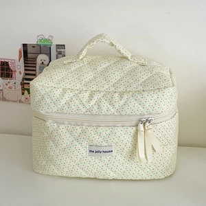 Detail of cream quilted cotton makeup bag with colorful polka dots and silk ribbon zipper