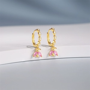 Close-up of golden bee earrings with pink marquise wings and white zircon studs