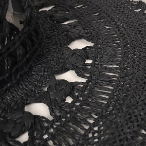 Dettaglio ravvicinato della trama intrecciata a mano e dei trafori su un cappello di paglia nero
