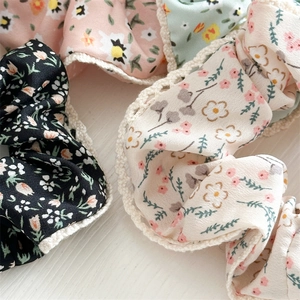 Close-up of floral fabric hair scrunchies with white lace edges in various colors