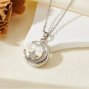Détail du collier avec pendentif lune et étoile en argent sur un support en pierre blanche