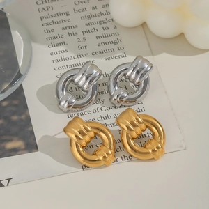 Close-up of gold and silver chunky chain link earrings on a vintage paper background