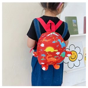 Detail view of red kids backpack with cartoon dinosaur prints and 3D claws on a child