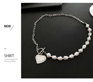 Detail of pearl necklace with silver chain and white heart pendant on black background