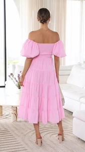 Back view of a pink off-shoulder smocked midi dress with puff sleeves and tiered skirt