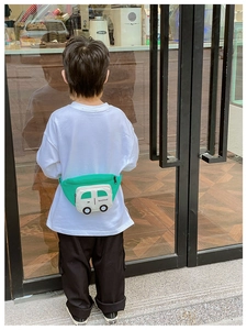 Kids cartoon car-shaped chest bag in green and white worn on back by model outdoors