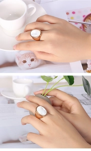 Detailed view of an oversized oval shell ring in rose gold finish on a hand