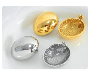 Detailed close-up of oval geometric earrings in polished gold and silver steel finish