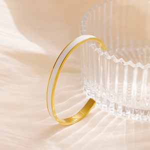 Eleganter goldener C-förmiger Edelstahl-Armreif mit weißem Emaille-Inlay auf Seide