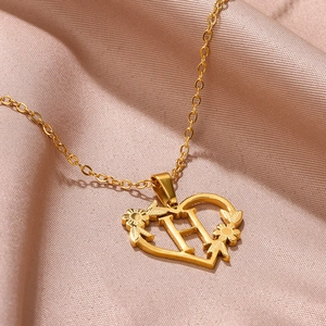 Dettaglio macro della collana a cuore dorata con lettera H e incisione a girasole