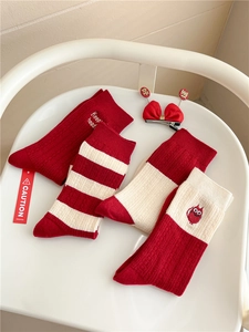 Detail view of red and white festive knit socks with striped patterns and embroidery