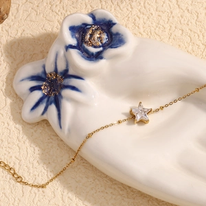 Detail of 18K gold plated chain bracelet with a star-shaped crystal on a ceramic tray