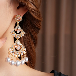 Golden fan tassel earrings with pink gems and pearls shown on a model