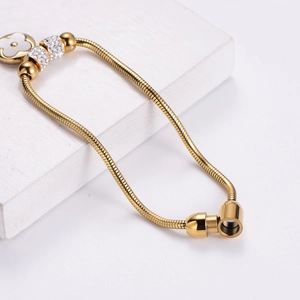 Gold snake chain bracelet with white clover charm and sparkling rhinestone accents