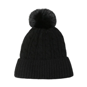 Détail du bonnet en tricot torsadé noir avec grand pompon en fourrure et revers côtelé