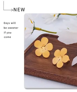 Detailed macro view of gold five-petal flower earrings with a matte brushed metal finish