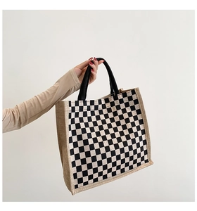 Detail of checkered tote bag featuring woven black handles and natural jute side texture