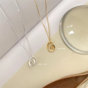 Detail of interlocking irregular gold and silver ring pendants on a minimalist chain