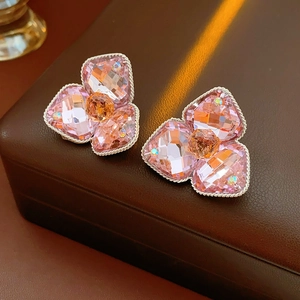 Macro shot of pink crystal flower stud earrings with silver twisted metal on leather background