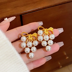Close-up of gold bow earrings with clustered white pearls for a vintage jewelry look
