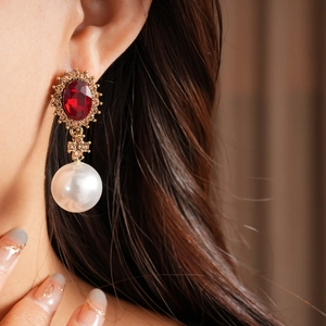 Gros plan de boucles d'oreilles vintage en perles et pierres rouges avec base dorée