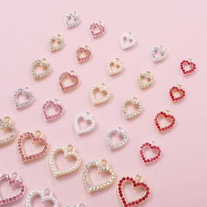 Detailed close-up of hollow heart-shaped nail charms with rhinestones and pearls