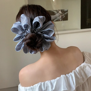 Detail of oversized black and white gingham scrunchie on a chic low bun hairstyle