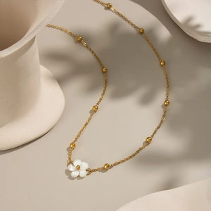 Close-up of a minimalist 18K gold plated flower necklace with white shell pendant detail