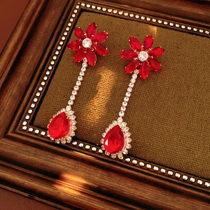 Detail of red crystal drop earrings with flower studs and sparkling zirconia in wooden frame