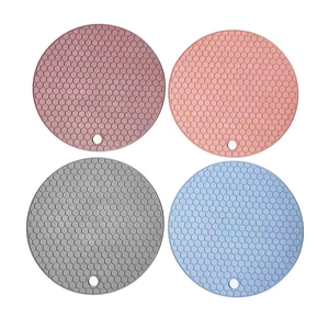 Vue de dessus de quatre dessous de plat ronds en silicone colorés avec texture en nid d'abeille
