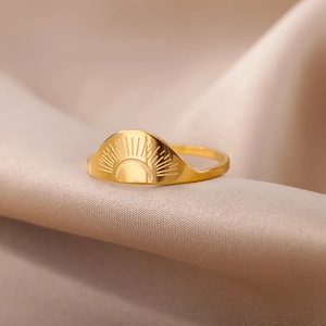 Detailed view of sunburst engraved 18K gold stainless steel ring on silk background