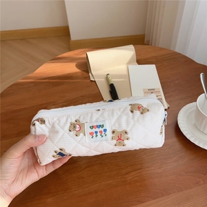 Macro detail of quilted beige pencil case with bear patterns and BEST woven label