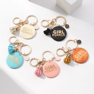 Macro detail of handmade GIRL mama wooden tag keychains with tassels in five colors