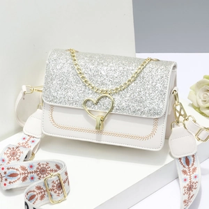 Elegant white crossbody bag with silver glitter lid, gold heart lock, and ethnic strap