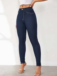 Detail of high waisted skinny jeans in dark blue with white contrast stitching accents