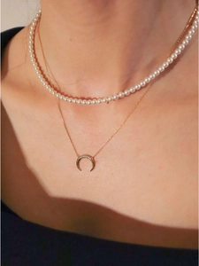 Double layered gold necklace set with white pearls and a sparkling crescent moon pendant