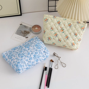 Detailed view of quilted floral cosmetic bags in blue and yellow on a white desktop