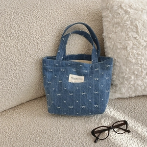 Gros plan du sac à main en denim bleu avec broderies de nœuds blancs et cœurs