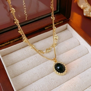 Close-up of gold plated double-layer heart necklace with black oval gemstone pendant