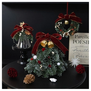 Detail of mini Christmas tree and pine wreath with red velvet bows and golden bells
