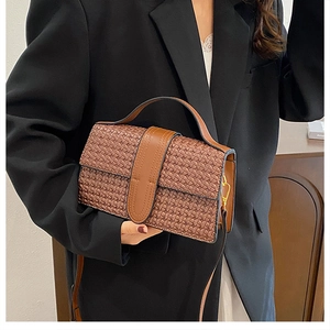 Close-up of brown woven texture on vintage style shoulder bag with gold hardware