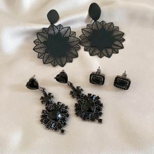 Detailed set of black floral, heart-shaped, and rectangular gemstone earrings on silk
