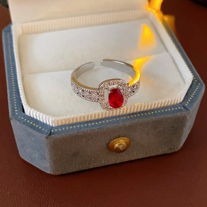 Detail of silver adjustable ring with oval red gemstone and zircon accents in box